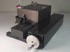 Dover Instrument Corp precision linear slide — front-left 3/4 view showing black anodized chassis, large carriage block, aluminum handwheel with knurled rim, star locking knob, and pneumatic gas inlet fitting on top