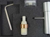 Hex key wrench, ceramic and copper ring component, clear plastic container, and stainless steel cylindrical tool laid out in foam