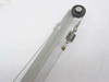 Close-up of linear carriage rail arm showing steel drive cable, tension spring, and end pulley detail
