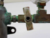 Close-up of brass needle/stopcock shutoff valve on manifold outlet showing T-bar handle and port opening