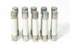 Fusetron MDA-10 dual-element ceramic fuses – group of 7 standing upright showing ceramic body and metal end caps