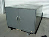 Gray steel 2-door industrial storage cabinet with bar-style handles and casters, front-left three-quarter view
