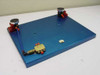 Air Safety dual hand safety switch — front three-quarter view showing both palm button assemblies, Clippard brass pneumatic valve at lower left, and blue tubing routing across plate