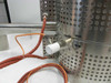 Close-up of furnace shell side showing thermocouple bracket mount, white ceramic thermocouple probe tip, orange high-temperature lead wires, and stainless perforated housing