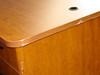 Close-up of desk corner showing finish marring and laminate chipping at the top edge near corner