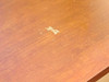 Close-up of desktop surface showing white finish marring and small paint or laminate chip on the work surface