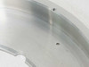 Close-up of stainless steel vacuum flange ring surface showing machined finish, one installed screw and one open mounting hole
