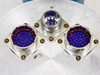 Close-up of three MIL-spec multi-pin electrical feedthrough connectors on aluminum vacuum chamber flange — two large square-flange ~37-pin connectors with blue inserts (marked H2050/DE1-H2050) and one smaller center round connector