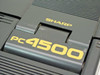 Sharp PC-4500 lid hinge close-up showing gold SHARP and pc4500 lettering on dark grey clamshell body