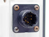 Close-up of 8-pin circular male connector on acrylic enclosure panel — gold-plated pins, black housing, four mounting screws with surface oxidation