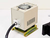 Beige fiber optic light source unit close-up showing top-mounted cooling fan, side ventilation slits, fiber optic cable output, and gold-colored mounting feet