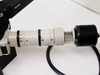 Close-up of fiber optic illuminator barrel assembly with threaded focusing rings and black end cap, attached to Pulnix TM-745 camera mount