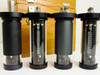 Four Texas Instruments fused quartz Bourdon tube sensor capsules close-up — two with visible coiled quartz tube elements through clear cylinder bodies, two with opaque black cylinders