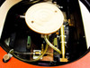 Interior view under orange stage — wafer chuck assembly, XY stage linear guides, brass lead screw/actuator, pneumatic tubing, and wiring harness visible