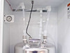 Close-up of stainless steel canister top inside FSI ChemFill bay showing polypropylene tubing connections and liquid level sensor wire