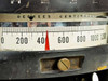 Close-up of Wheelco Model 402 meter scale face showing Degrees Centigrade graduations from 0 to 1200 with red pointer and brass gear adjustment knob, partial serial number label visible below scale
