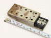Schneeberger NK 2-80 linear positioning slide shown fully extended next to ruler — top view showing tapped mounting holes and surface wear