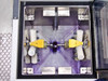 Interior of wafer mask cleaning chamber top-down view showing spray nozzle cross pattern, yellow mask/wafer holders, white roller guides, and stainless steel chamber walls