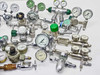Angled view of regulator and gauge lot highlighting Welco vacuum gauge, green-cap regulator, inline filter/separator, and chrome needle valves arranged on white surface