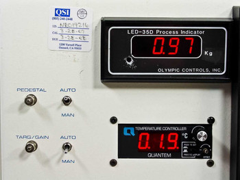 Research Devices M9 rework station controller console – close-up of Olympic Controls LED-35D process indicator reading 0.97 Kg and Quantem Temperature Controller reading 0.19°C, with PEDESTAL and TARG/GAIN AUTO/MAN toggle switches; QSI calibration label visible