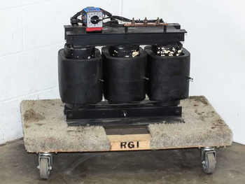 Varian MED 01-000062-00H 12kVA three-phase transformer — front-left view showing three black coil cores on steel base frame with Kraus & Naimer rotary tap selector and wiring harness on top