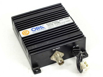 ORA Electronics ID3000 Booster Amplifier – front-left view showing BNC input connector and DC 12V power connector with heatsink enclosure