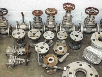 Close view of mixed stainless steel flanged gate valves and pipe flange fittings showing variety of sizes and handwheels
