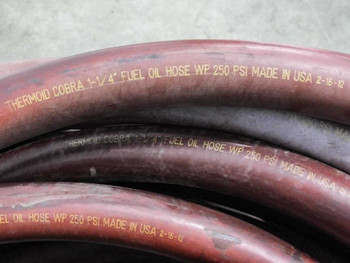 Thermoid Cobra 1-1/4" fuel oil hose close-up showing embossed text: THERMOID COBRA 1-1/4" FUEL OIL HOSE WP 250 PSI MADE IN USA 2-16-12