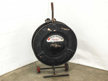 Signode DD-1A mobile plastic strapping dispenser — front view showing circular reel housing, handle, and red wheeled base