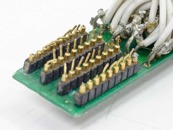Close-up of internal PCB breakout end showing gold solder pins and multi-conductor white wire terminations
