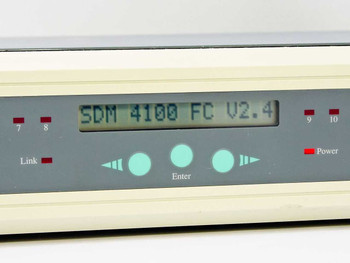Astrocom 4100 front panel display showing SDM 4100 FC V2.4 firmware, navigation buttons, and port indicator LEDs 7–10