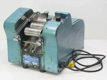 Burnett Bros Engineering industrial label applicator front-left view showing blue cast housing, roller mechanism, and power cord with plug