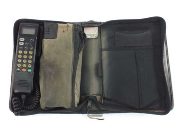Motorola SCN2449A bag phone open in travel bag showing handset on left and accessories compartments with car charger on right