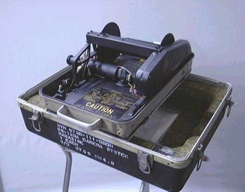 Dyna Metric KS-123A camera system open in transit case showing camera body, film transport mechanism, and Caution placard with federal stock label