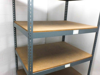 Boltless steel rivet shelving — close view of two middle shelves showing particle board surface and gray steel uprights