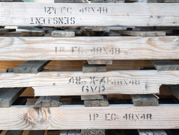 Close-up of pallet deck boards with stenciled markings reading 48x48 and other stamp codes visible