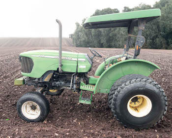 John Deere 5425 utility tractor — left side profile view showing open canopy, turf tires, operator platform, and fender detail in plowed field