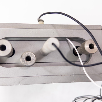 Wafer process chuck – side end view showing three threaded tube fittings with black and white tubing and wiring attached to ribbed aluminum housing