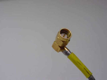 Close-up of gold-plated SMA male right-angle connector on yellow-jacketed flexible RF cable showing connector detail