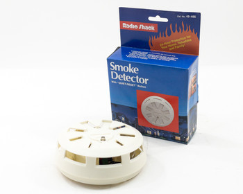 Radio Shack 49-466 Smoke Detector unit shown beside its original retail box with Quiet-Reset labeling visible