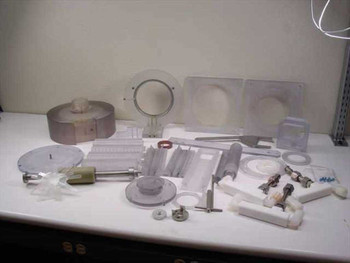 Full lot of plastic mixer spare parts spread on workbench — rotor bowl, impeller, blades, seals, fittings, and hardware