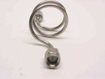 Close-up front view of SMA male connector end on stainless steel coiled semi-rigid coaxial cable showing gold center pin