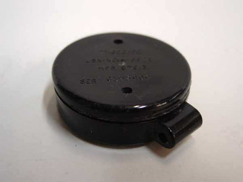 IECH DT-60C/PD Radiac Detector badge – closed black circular housing showing top face with embossed text and attachment tab