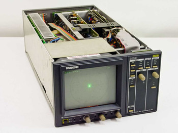 Magni VS561 PAL/NTSC/CAV Vectorscope – three-quarter front view showing powered CRT display with green dot trace and open top with internal PCBs and power supply exposed due to missing covers