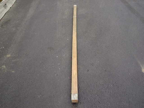 US Tucker Mfg Co military wood ridge tent pole, 9 feet long, laid flat on pavement — full length overhead view showing natural wood and metal end cap