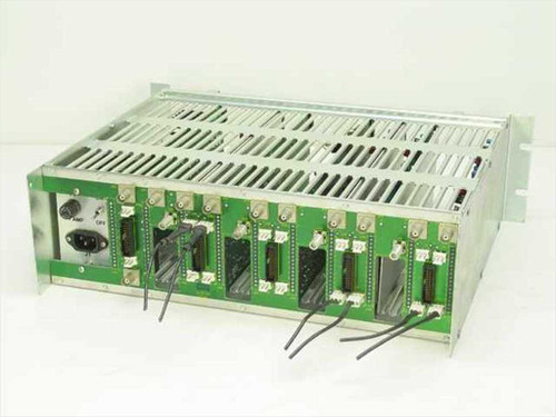 Wegener Communications 1601-54 Rev A Series 1600 mainframe rear three-quarter view showing green backplane PCB with card-edge connectors, IEC AC inlet, and ribbon cable leads