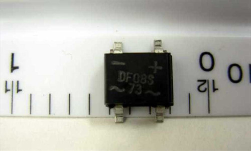ON Semiconductor DF08S SMD bridge rectifier single unit next to ruler showing approximately 5mm body width