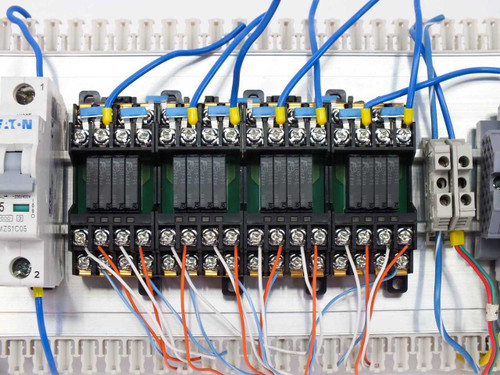 Close-up of RS4N-DE 4-relay card modules and Eaton WMZS1C05 mini circuit breaker on DIN rail with multi-color wiring