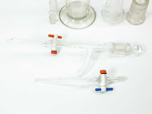 Lot of assorted laboratory glassware including tall graduated cylinder, adapter, buret with stopcocks, and small vials — overview