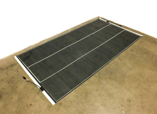 SoloPower SP3L-160 160W flexible CIGS solar panel laid flat on floor, angled overhead view showing full panel surface and MC4 cable at corner